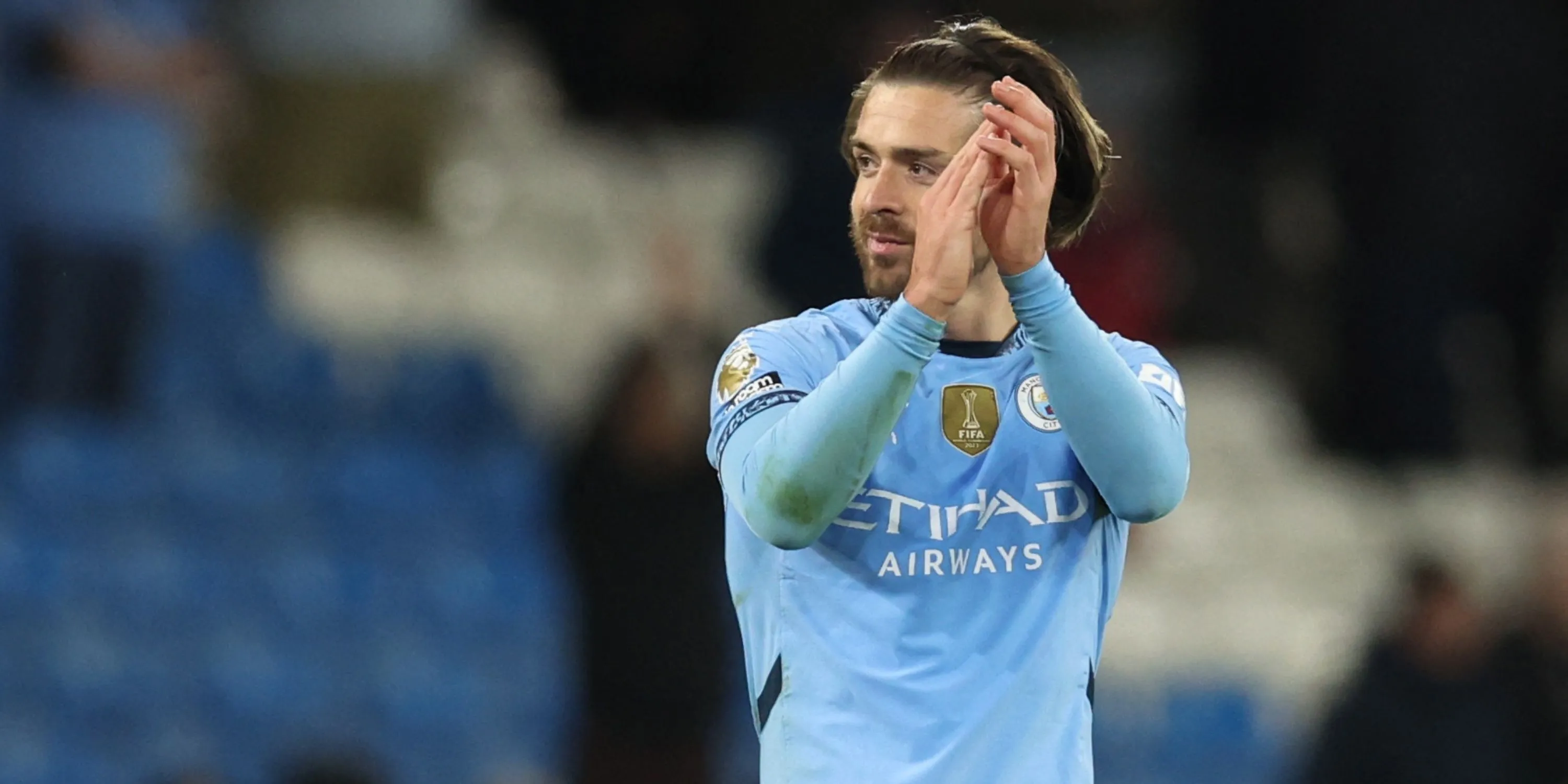 Jack Grealish trong màu áo Manchester City với biểu cảm nghiêm nghị trên sân cỏ.
